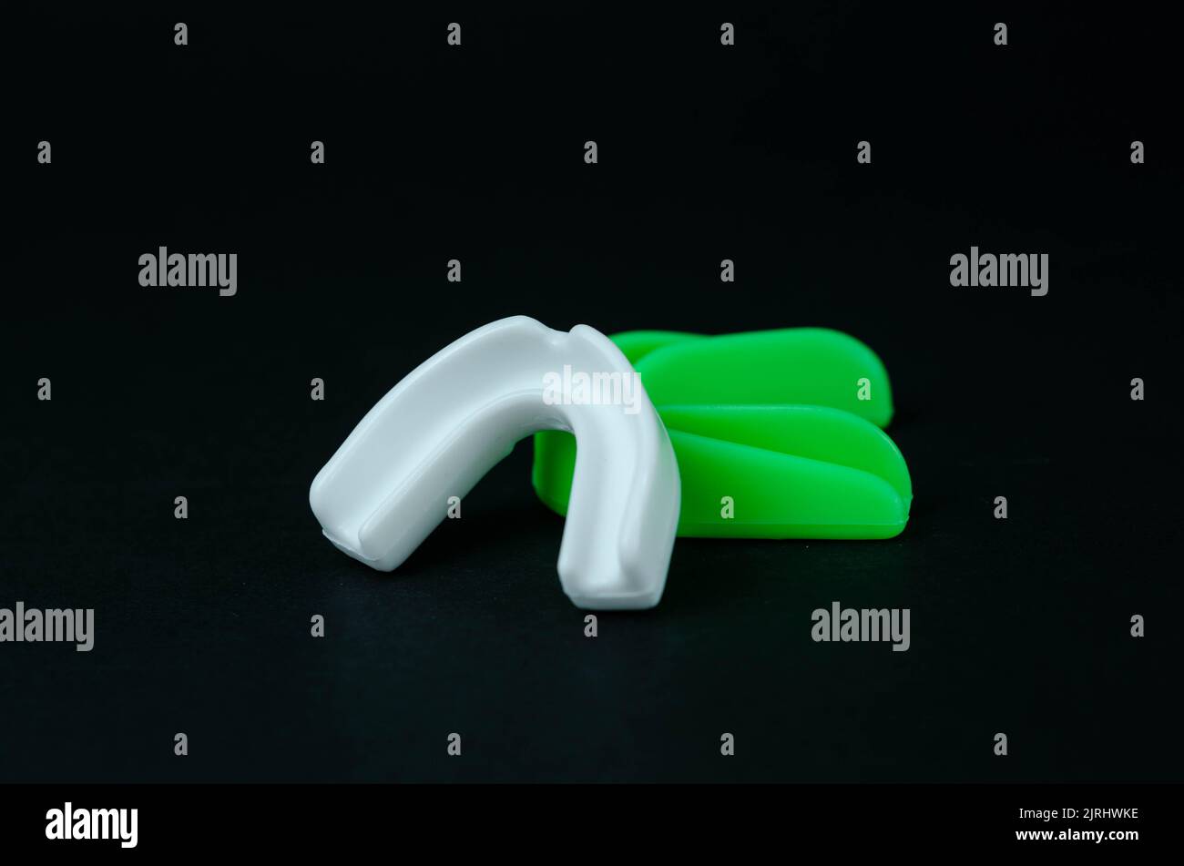 two rubber boxing mouth guards, white and green, protection for lips