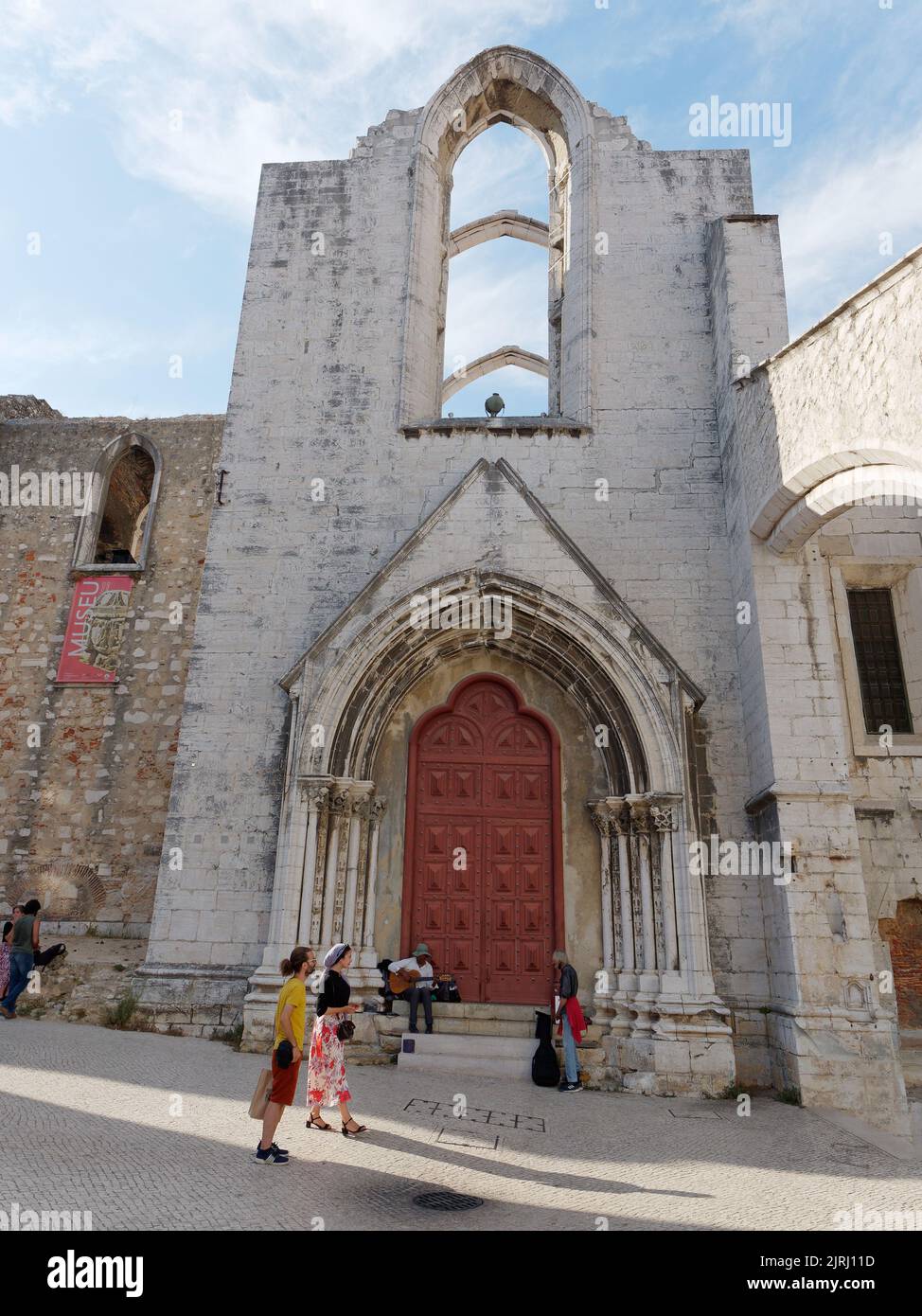 Carmo Church and Convent ruins entrance in Lisbon Portugal with trendily dressed tourists outside. Stock Photo