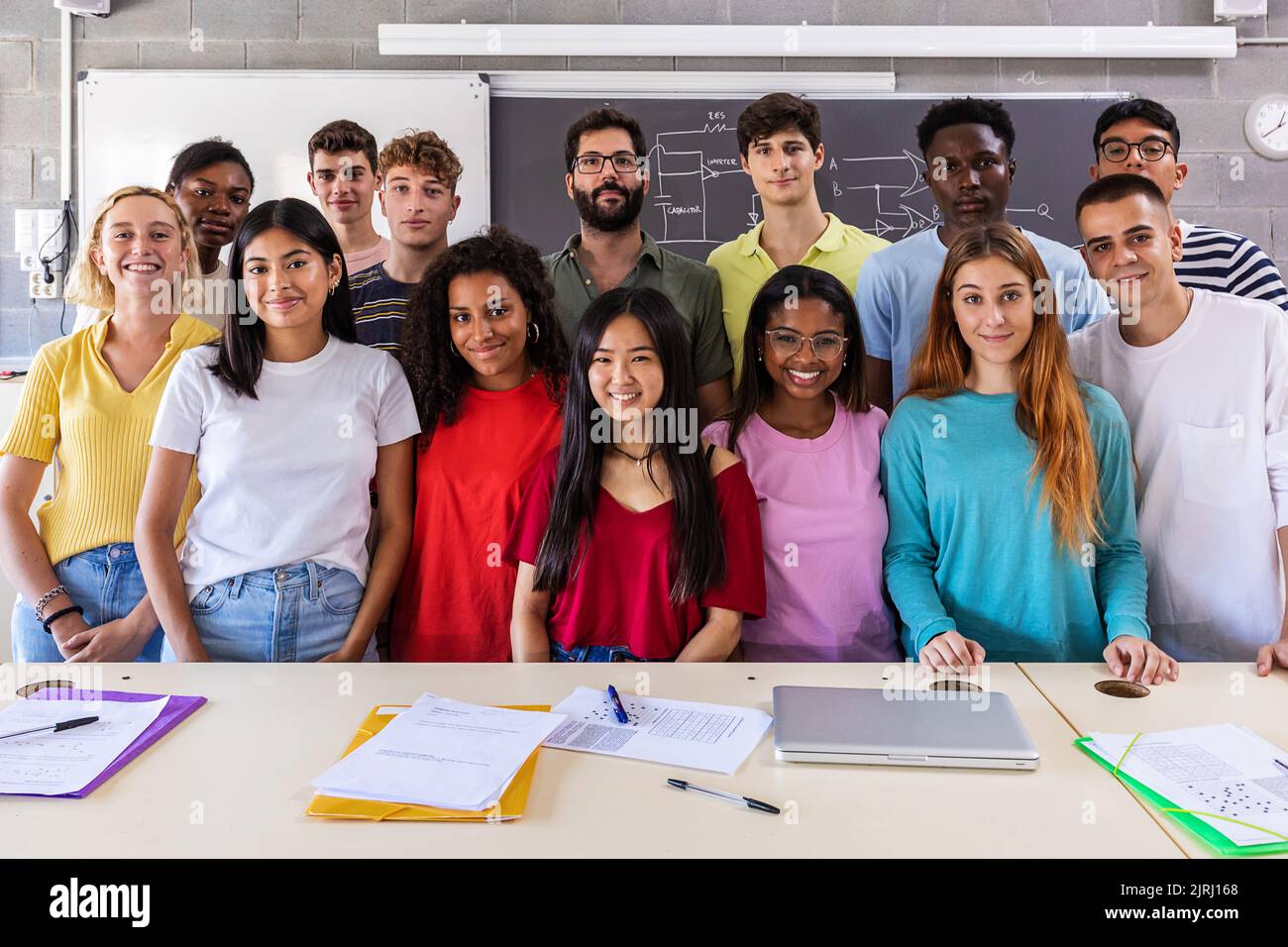 Portrait of smiling group of young multiracial students with teacher in class Stock Photo