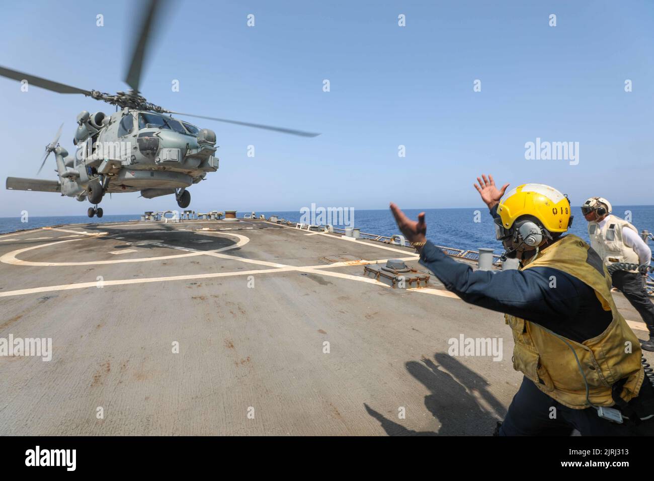 220818-N-CS075-1017 MEDITERRANEAN SEA (August, 18, 2022) Boatswain’s Mate 2nd Class Jerome Carlie, from Augusta, Georgia, signals to an MH-60S Seahawk helicopter, attached to the “Dragonslayers” of Helicopter Sea Combat Squadron (HSC) 11, aboard the Arleigh Burke-class guided-missile destroyer USS Cole (DDG 67) in the Mediterranean Sea, August 18, 2022. Cole is part of the Harry S. Truman Carrier Strike Group and is on a scheduled deployment in the U.S. Naval Forces Europe area of operations, employed by U.S. Sixth Fleet to defend U.S., allied and partner interests. (U.S. Navy Photo by Mass Co Stock Photo