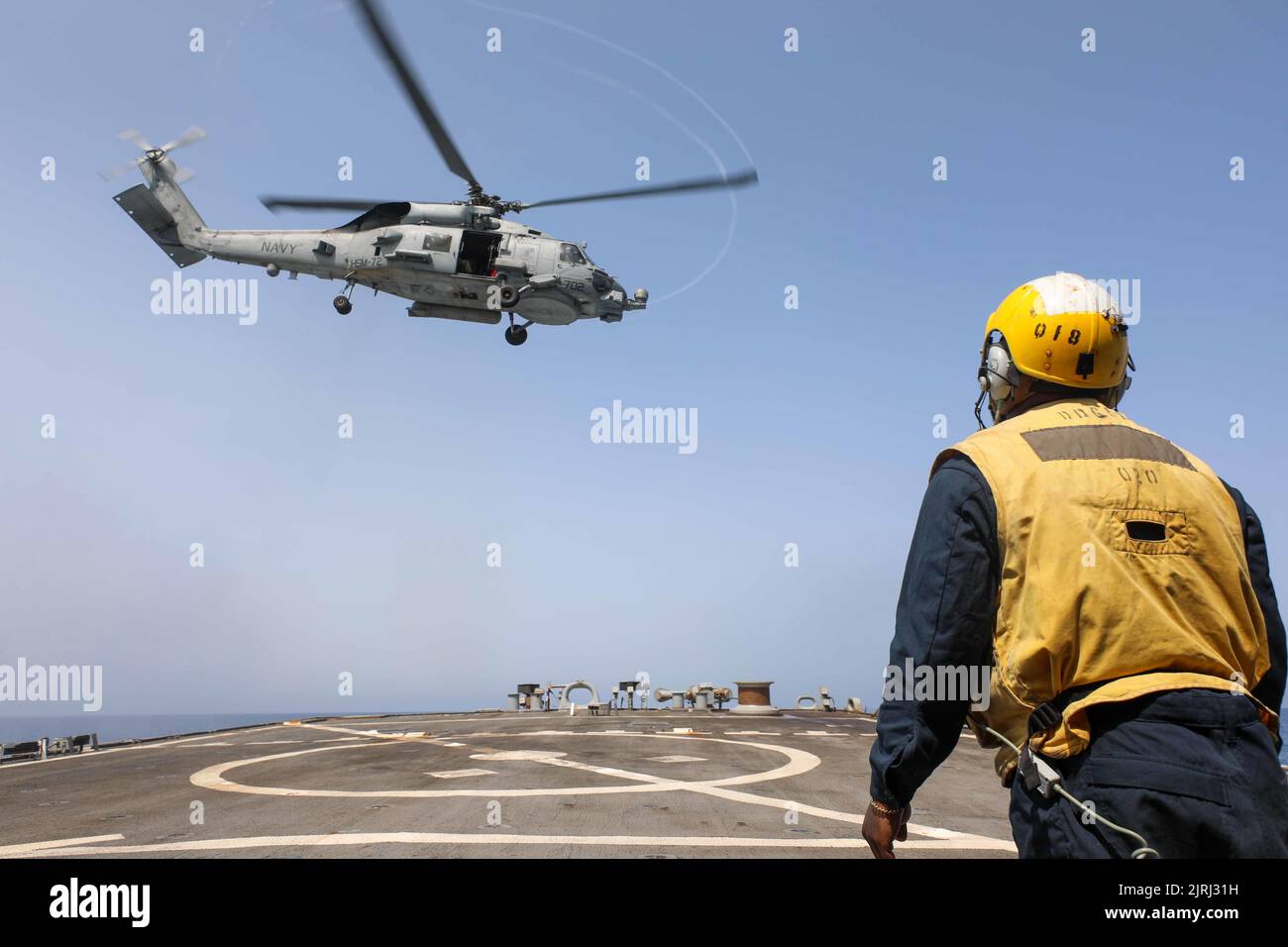 220818-N-CS075-1019 MEDITERRANEAN SEA (August, 18, 2022) Boatswain’s Mate 2nd Class Jerome Carlie, from Augusta, Georgia, signals to an MH-60S Seahawk helicopter, attached to the “Dragonslayers” of Helicopter Sea Combat Squadron (HSC) 11, aboard the Arleigh Burke-class guided-missile destroyer USS Cole (DDG 67) in the Mediterranean Sea, August 18, 2022. Cole is part of the Harry S. Truman Carrier Strike Group and is on a scheduled deployment in the U.S. Naval Forces Europe area of operations, employed by U.S. Sixth Fleet to defend U.S., allied and partner interests. (U.S. Navy Photo by Mass Co Stock Photo