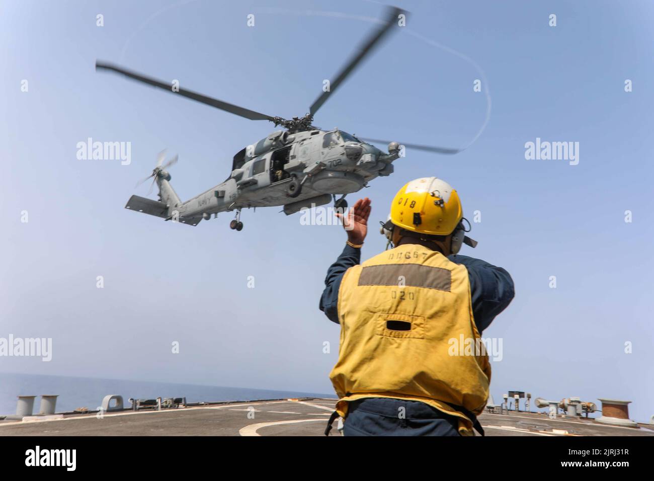 220818-N-CS075-1018 MEDITERRANEAN SEA (August, 18, 2022) Boatswain’s Mate 2nd Class Jerome Carlie, from Augusta, Georgia, signals to an MH-60S Seahawk helicopter, attached to the “Dragonslayers” of Helicopter Sea Combat Squadron (HSC) 11, aboard the Arleigh Burke-class guided-missile destroyer USS Cole (DDG 67) in the Mediterranean Sea, August 18, 2022. Cole is part of the Harry S. Truman Carrier Strike Group and is on a scheduled deployment in the U.S. Naval Forces Europe area of operations, employed by U.S. Sixth Fleet to defend U.S., allied and partner interests. (U.S. Navy Photo by Mass Co Stock Photo