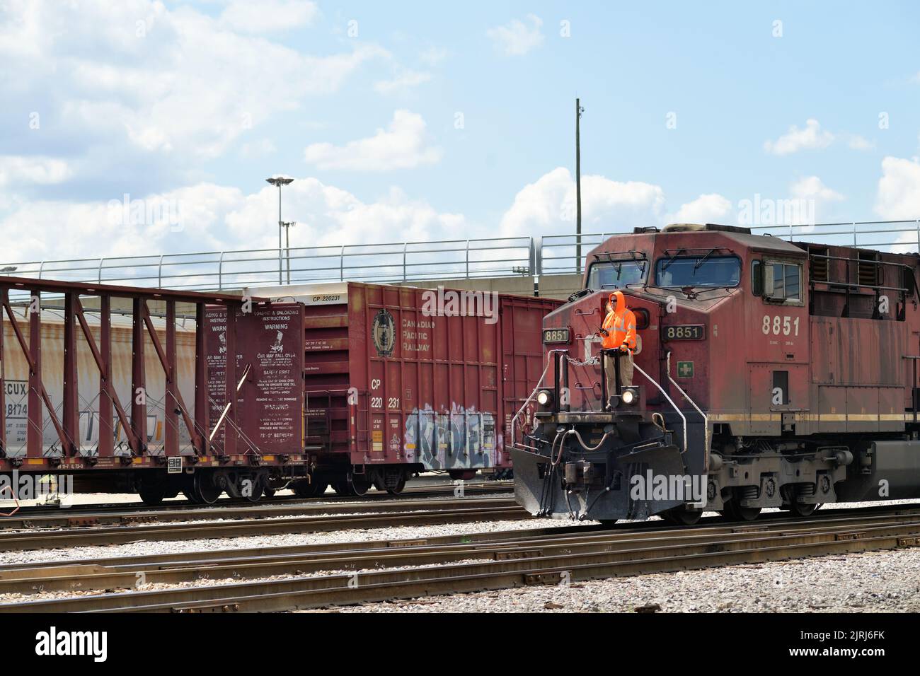 Franklin Park, Illinois, USA. With a crew member riding the front platform of the lead locomotive, a freight train departs a railroad yard. Stock Photo