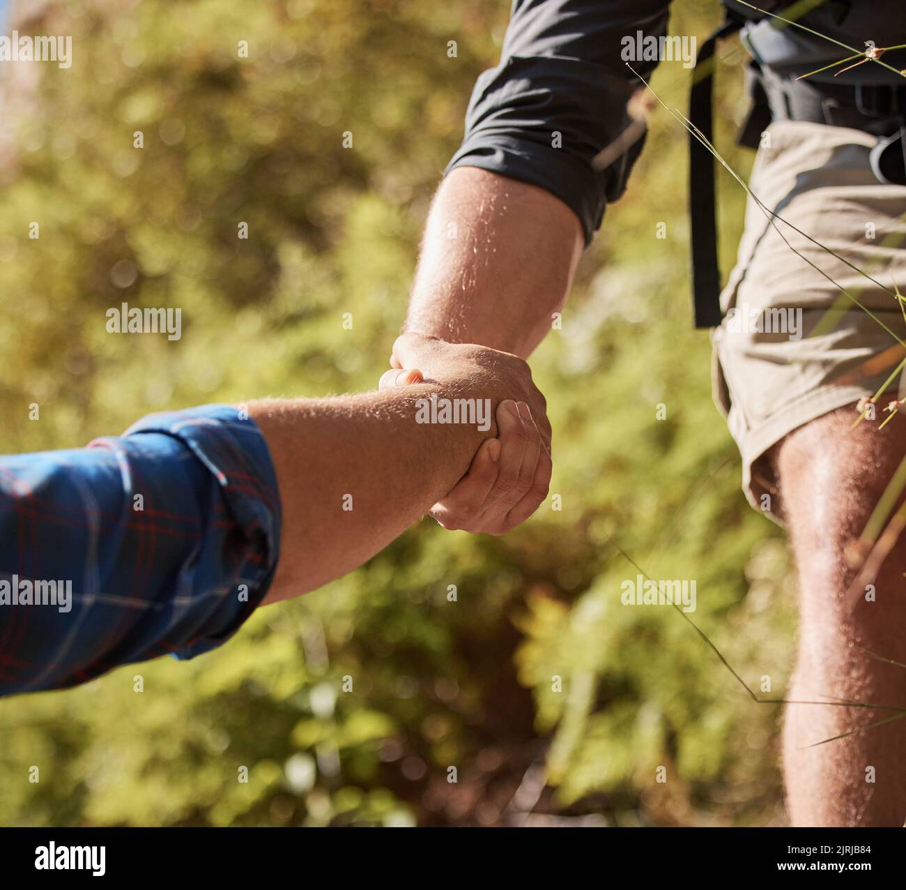 Support, teamwork and helping hands by hikers hiking outdoors in nature on a mountain trail. Fit and active friends help each other closeup and while Stock Photo