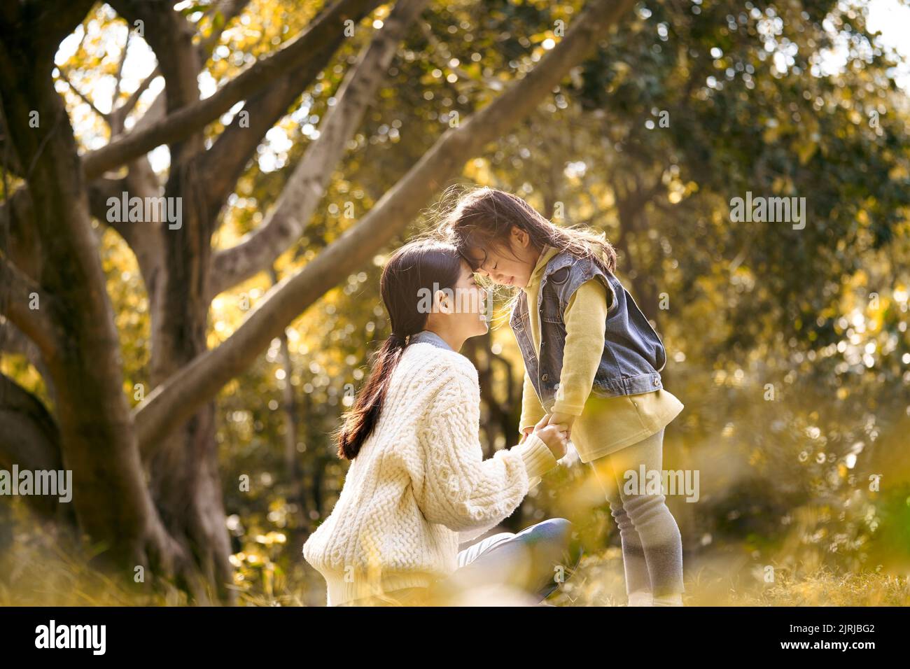 young asian mother and preschool daughter enjoying nature having a good time outdoors in park Stock Photo