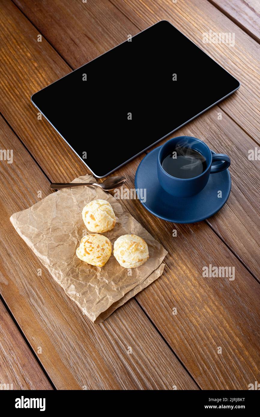 Brazilian cheese breads next to coffee cup, copper spoon and tablet ...