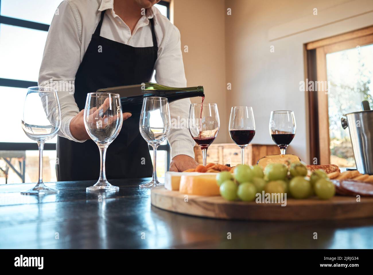Hospitality, industry, and luxury wine service with waiter pouring in
