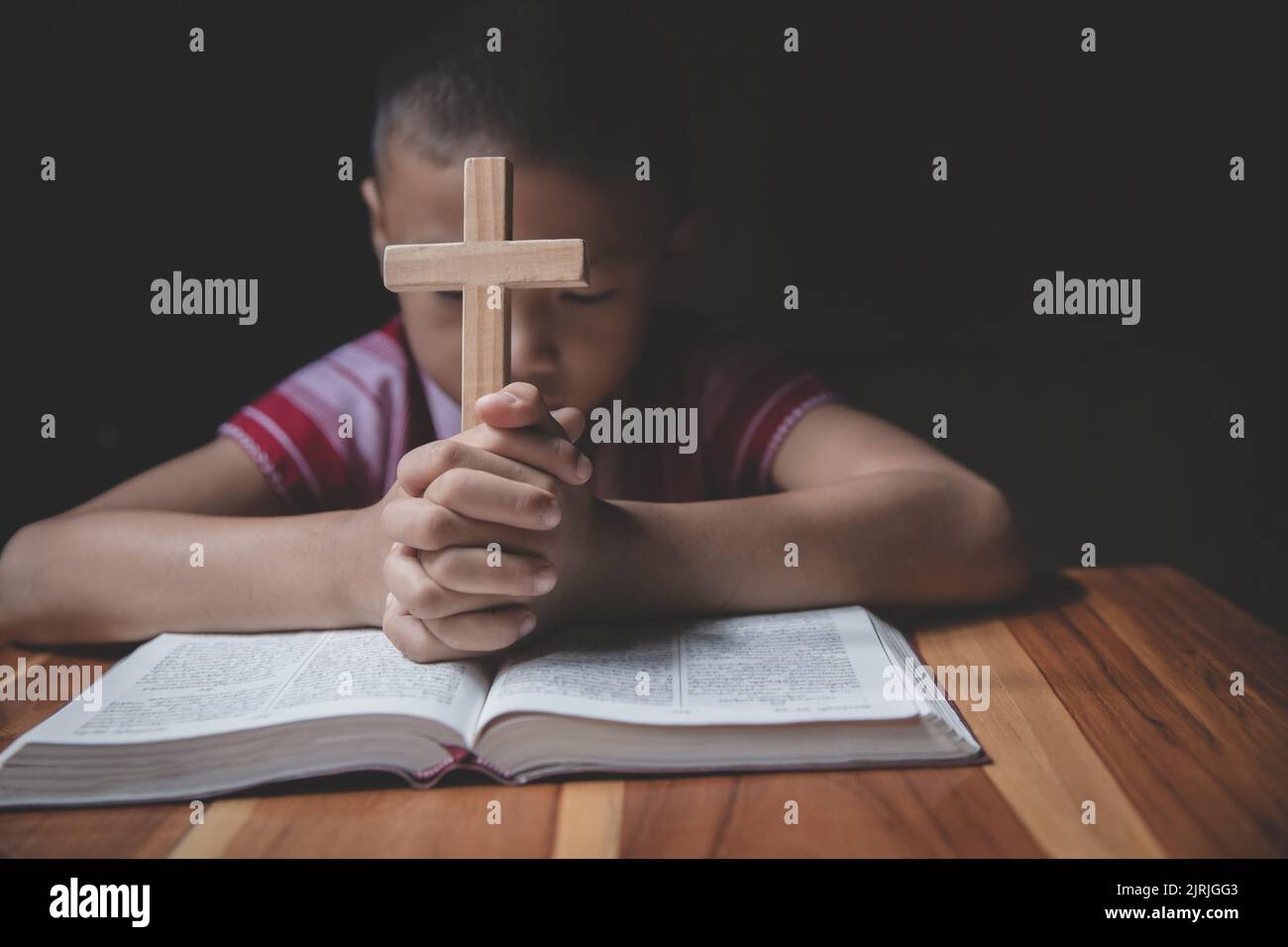 Boy hands holding a holy cross and praying to God, Child Praying for God Religion. Stock Photo