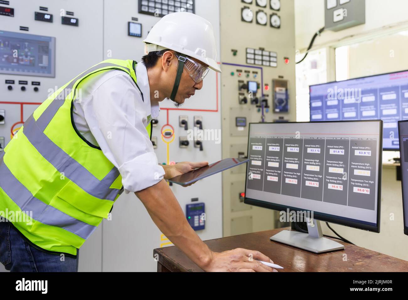 Experienced electrician working in a power plant control room. Engineer