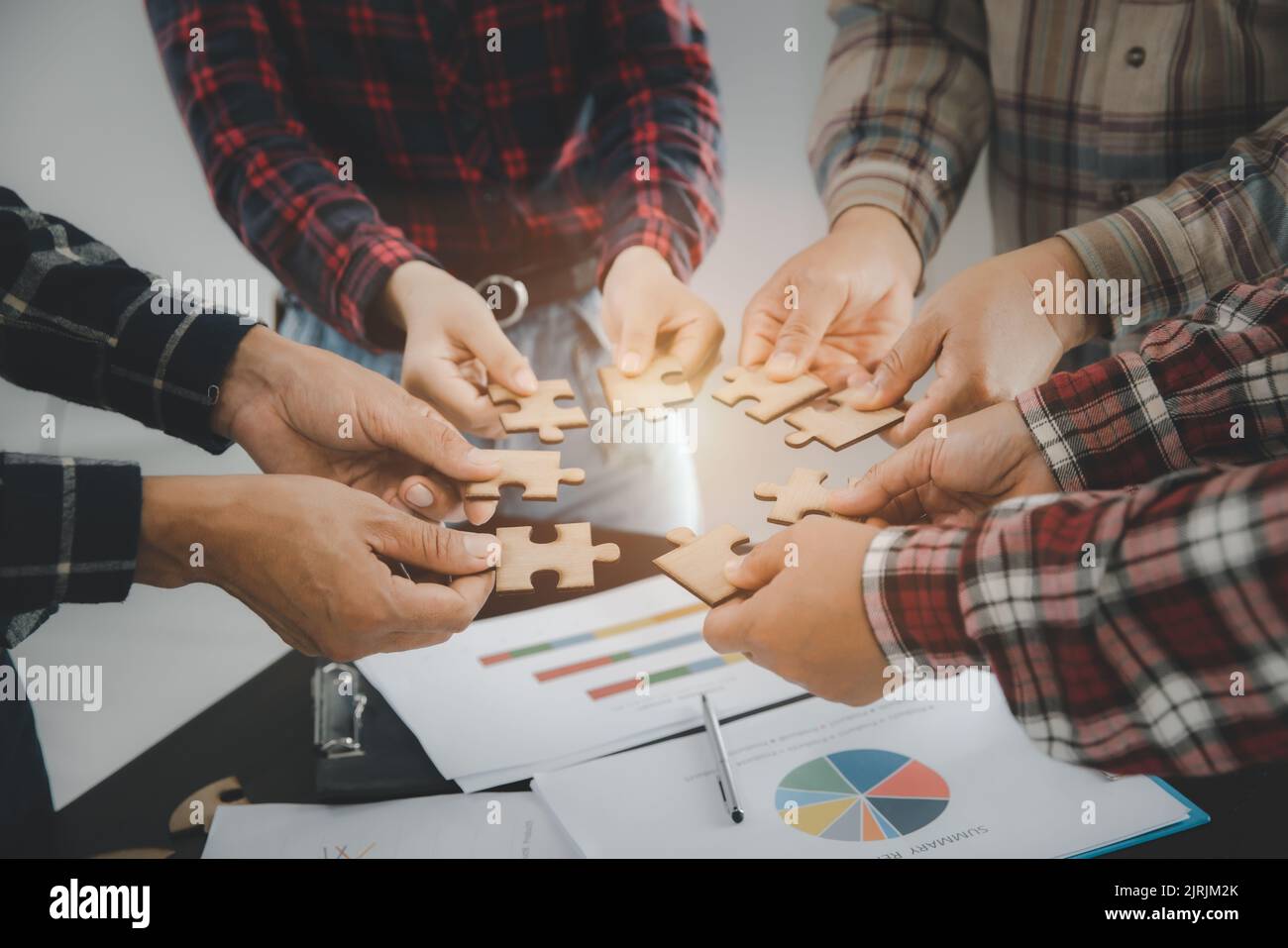 Hands of diverse people assembling jigsaw puzzle, team put pieces together searching for right match, help support in teamwork to find common solution Stock Photo