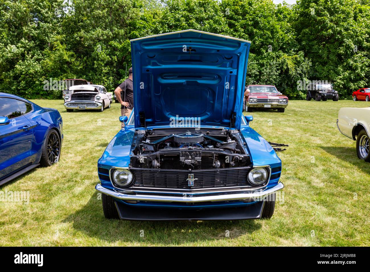 A classic blue 1970 Ford Mustang with its hood open for display at a