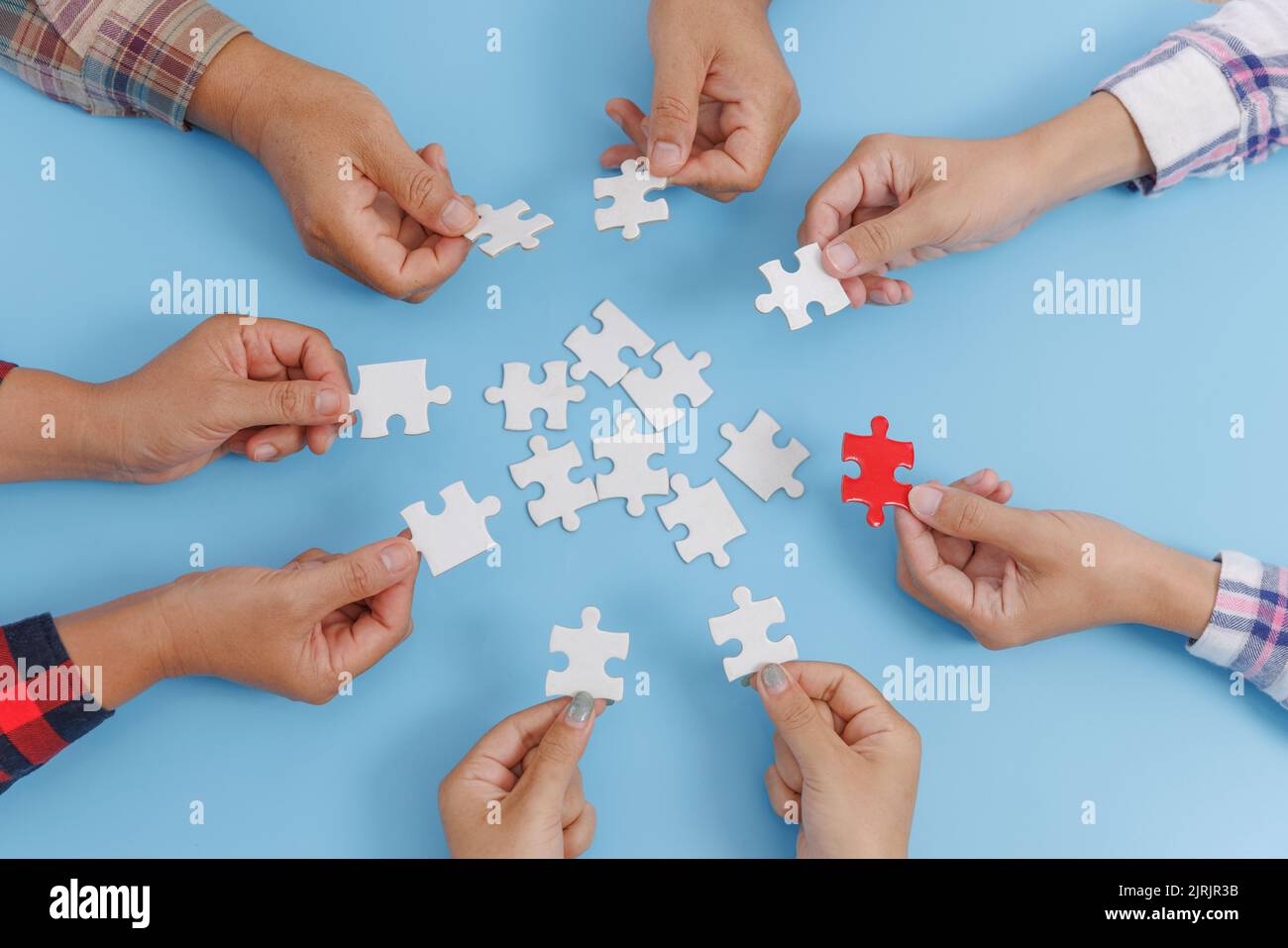 Hands of a group of people assembling jigsaw puzzle. Cooperation, teamwork  support concept Stock Photo - Alamy