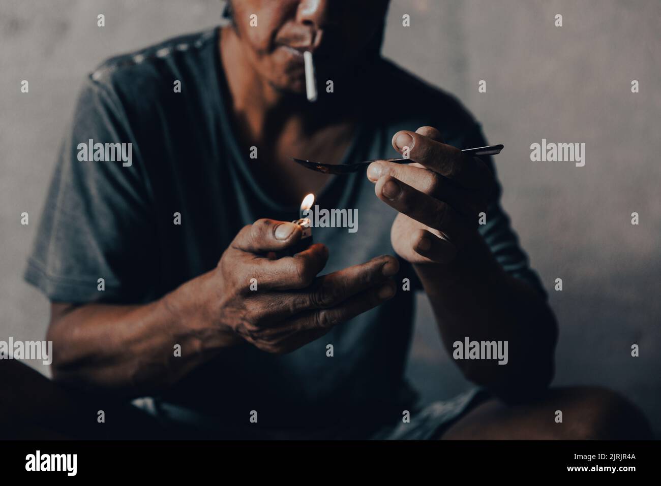 A junkie prepares pills with a spoon, lighter, heroin and syringes