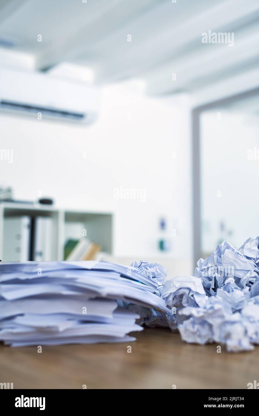 Somebody needs to catch up on some paperwork. a pile of crumpled up paperwork sitting on an office desk. Stock Photo