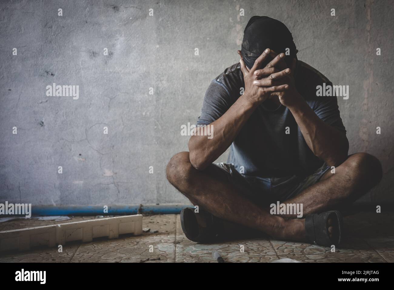 Depressed man sitting in abandoned building. Sad man crying. Drama. Lonely and unhappy concept, drug addict. Stock Photo
