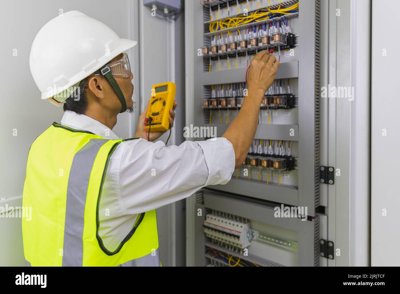 Electrician installing electric cable wires and fuse switch box