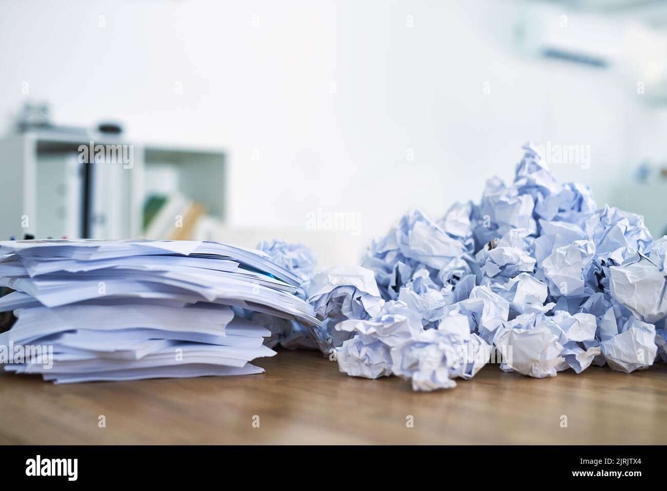 Paperwork is piling up. a pile of crumpled up paperwork sitting on an office desk. Stock Photo