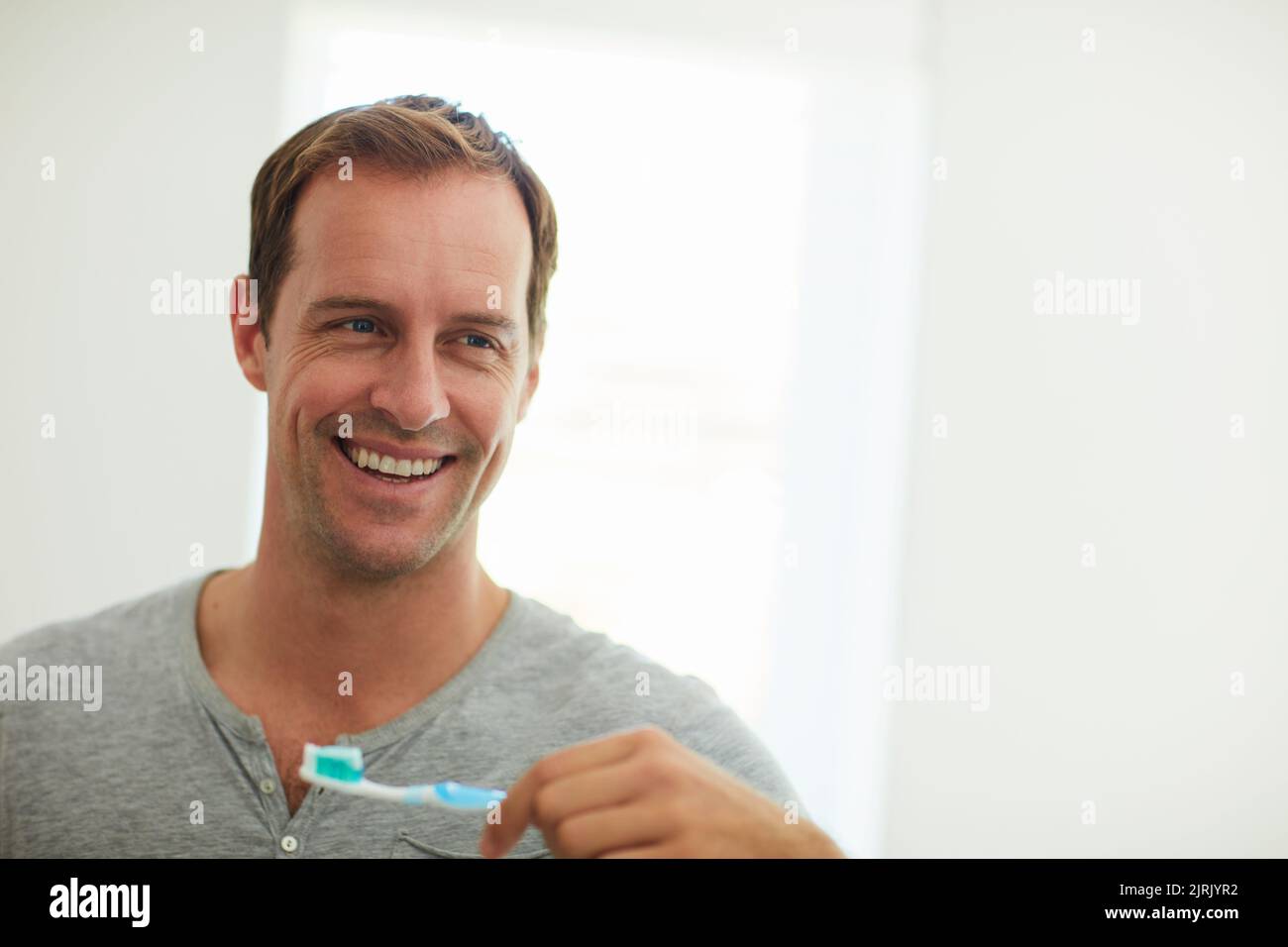 Good hygiene starts every morning. a man brushing his teeth in the