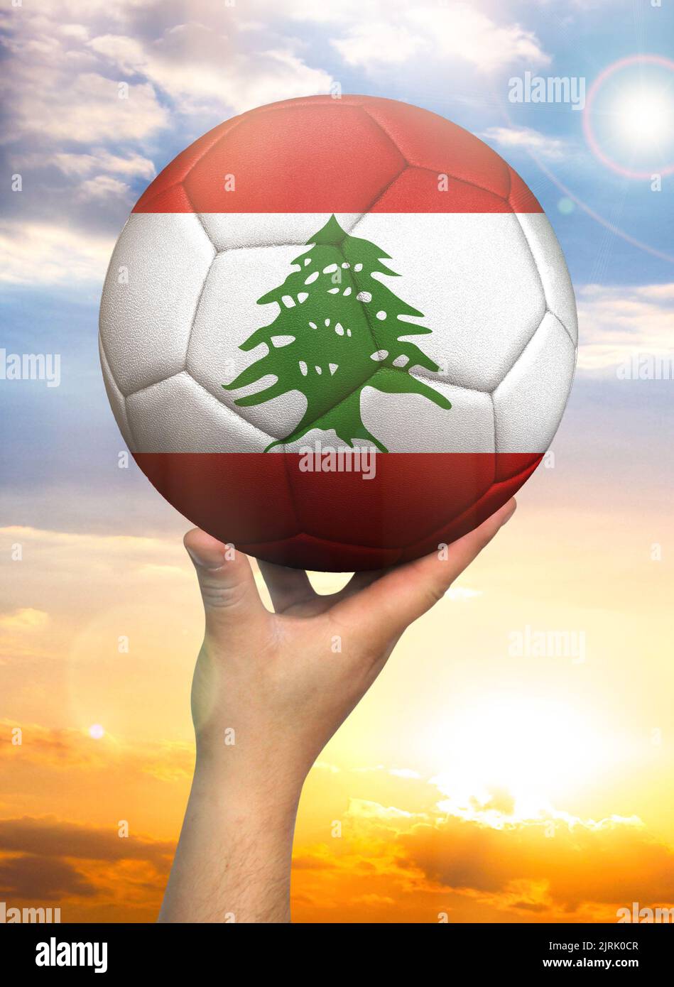 Soccer ball in hand with a depiction of the flag of Lebanon against a