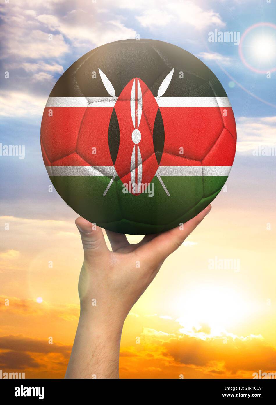 Soccer ball in hand with a depiction of the flag of Kenya against a