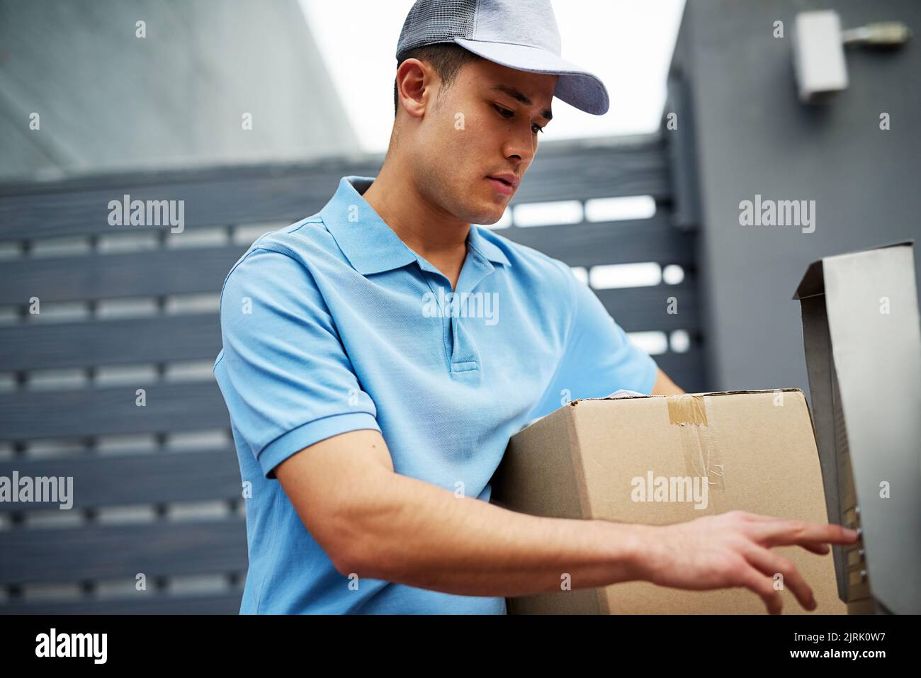 Doing his delivery rounds. a courier ringing an intercom while making a delivery. Stock Photo