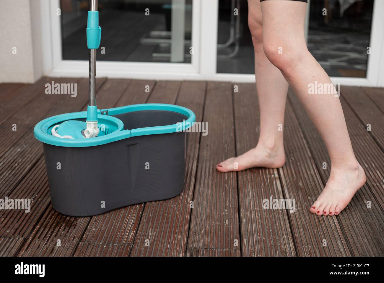 https://c8.alamy.com/comp/2JRK1C7/cropped-photo-of-young-barefoot-woman-holding-spin-mop-over-grey-plastic-bucket-cleaning-wooden-floor-of-veranda-2JRK1C7.jpg