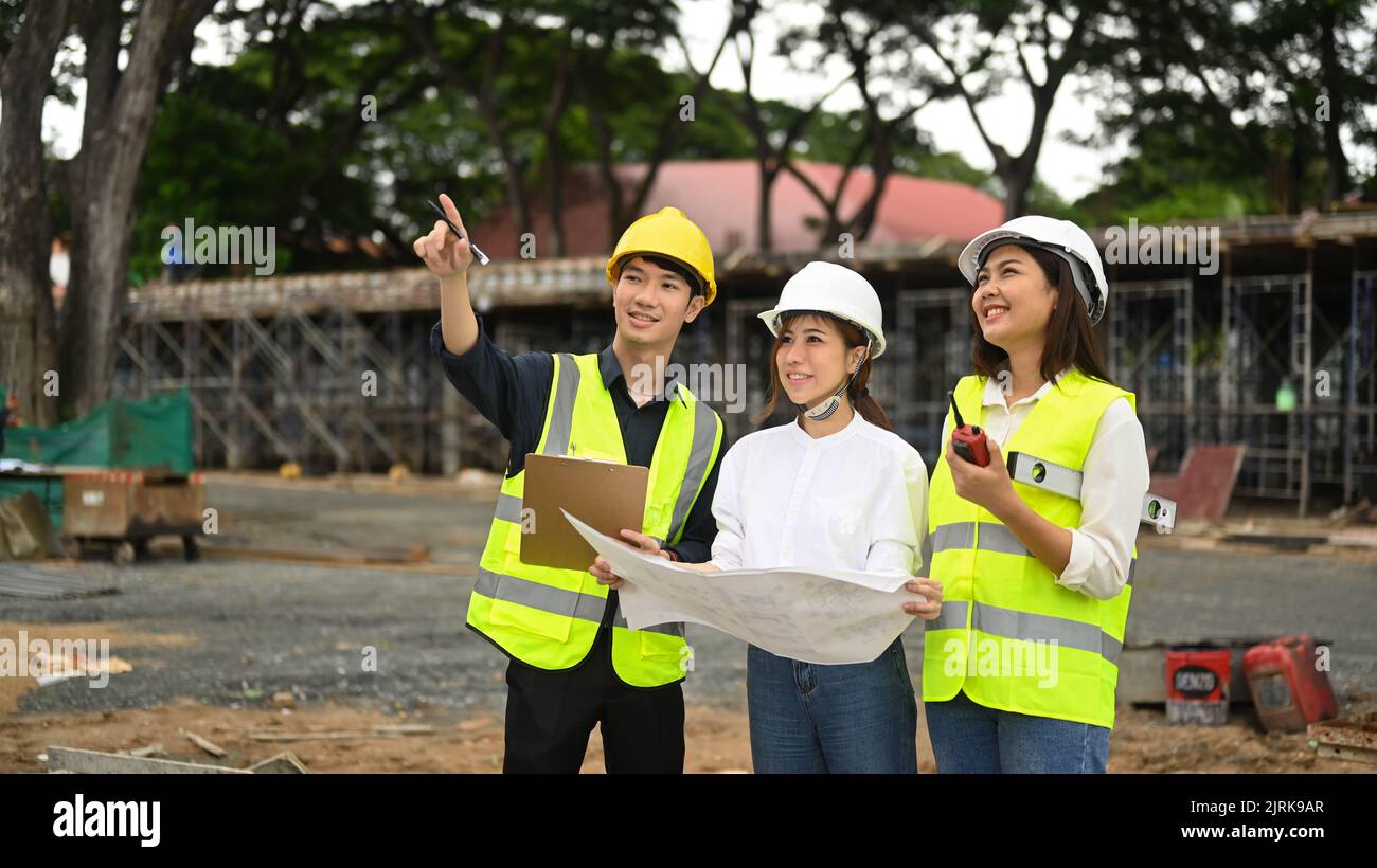 Team of civil engineers wearing safety helmets and vests examining
