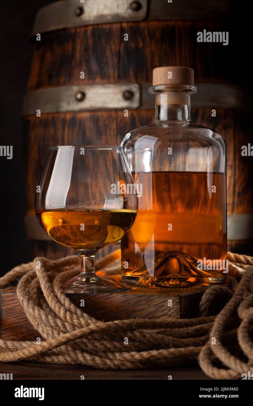 Glass and bottle with cognac, whiskey or golden rum. In front of old