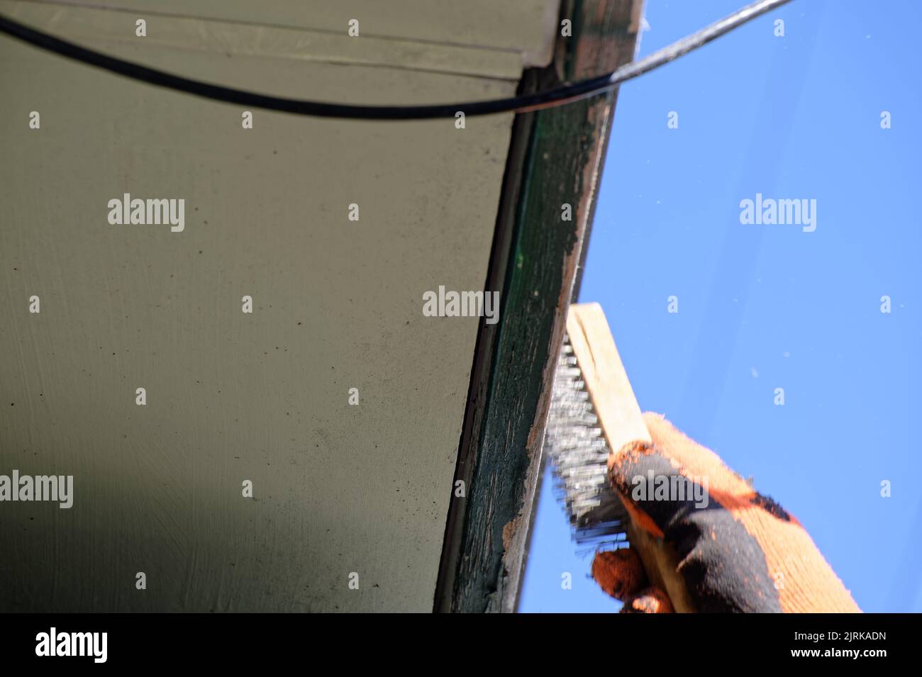 A close up of a wire brush being used to remove loose paint from a