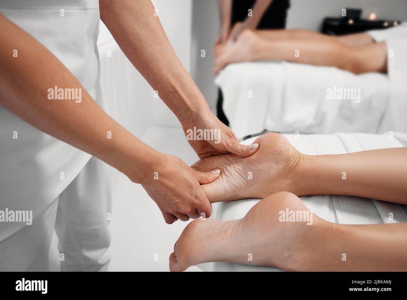 Foot massage with massage oil for female feet while relaxing and resting with her partner at spa while couple massage. Legs massage Stock Photo