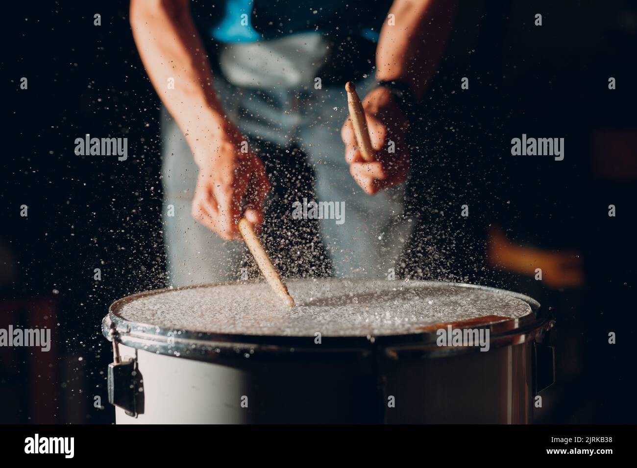 Close up drum sticks drumming hit beat rhythm on drum surface with splash water drops falling Stock Photo