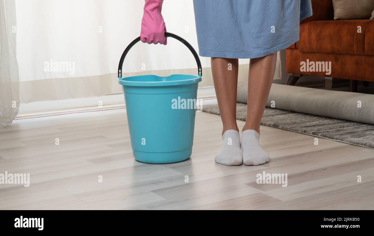 Housewife in gloves with a bucket to clean the apartment Stock Photo