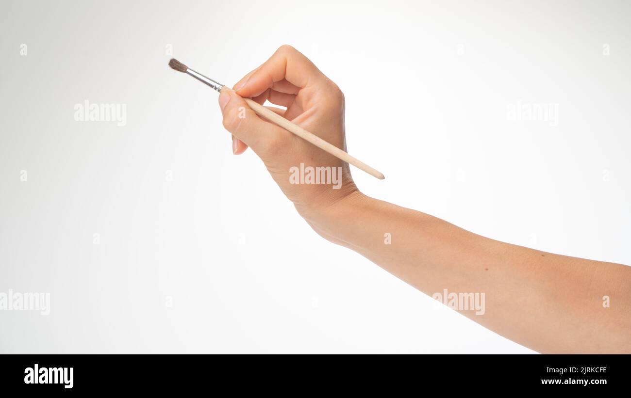 Drawing brush in a woman's right hand, gesture to draw on a white