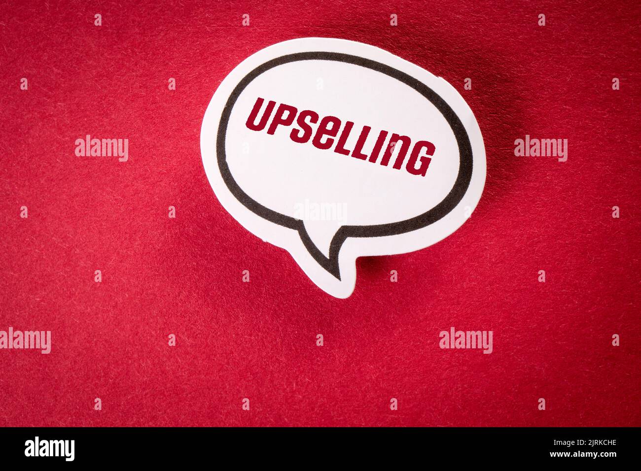 Upselling. White speech bubble with text on red background. Stock Photo