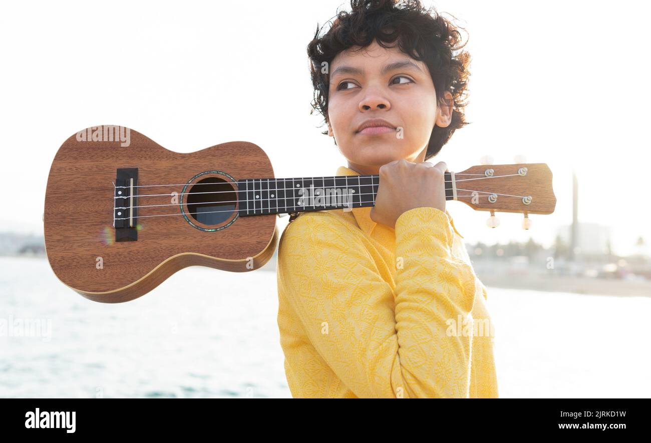 Side view of dreamy young ethnic woman with short curly hair holding