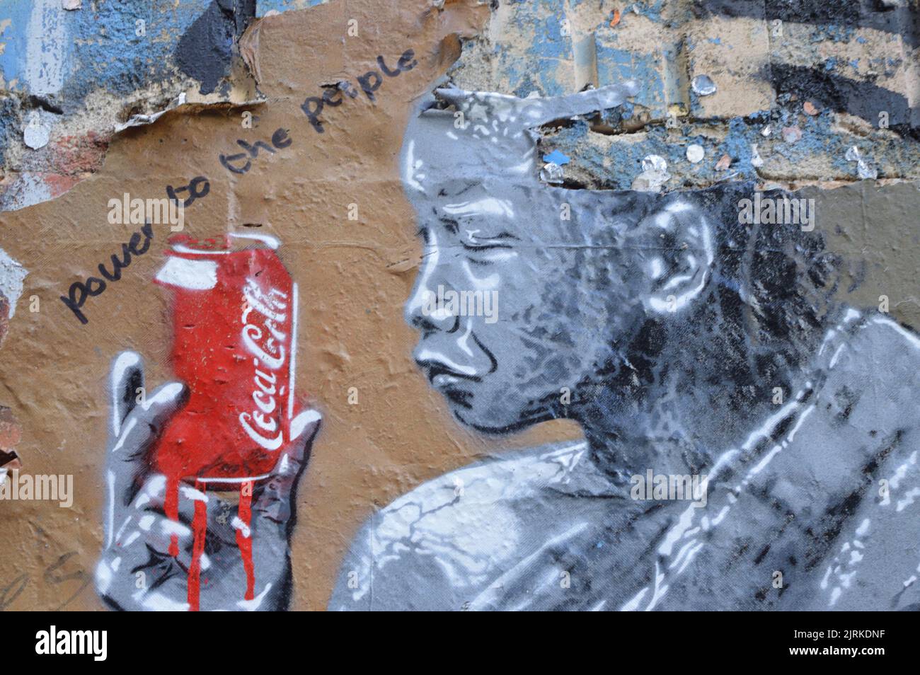 Graffiti street art of person holding a red bleeding can of Coca Cola