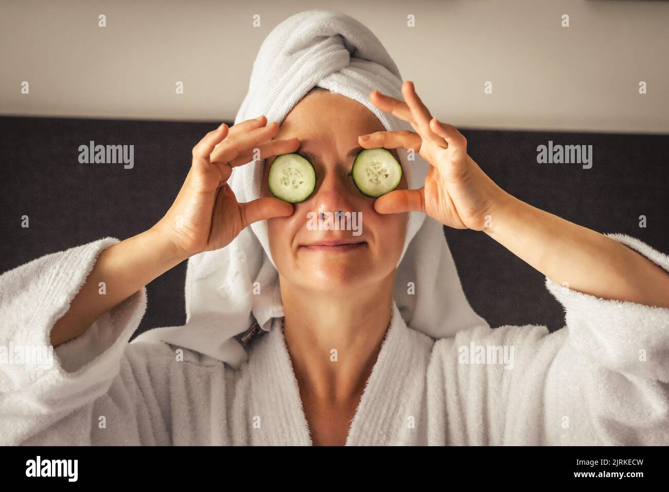 young woman getting eye nature treatment by cucumber at luxury spa resort. Wellness and healing concept. Stock Photo