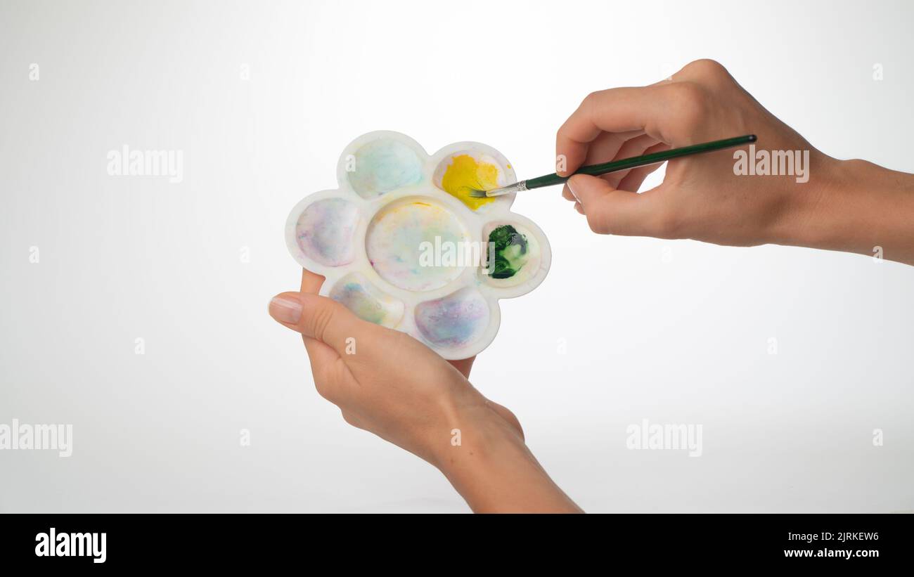 Women's hands with palette and brush, gesture to mix paint. High quality photo Stock Photo