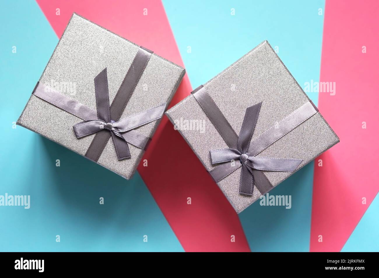 Two silver gift boxes on a blue and pink background. Flat lay Stock Photo