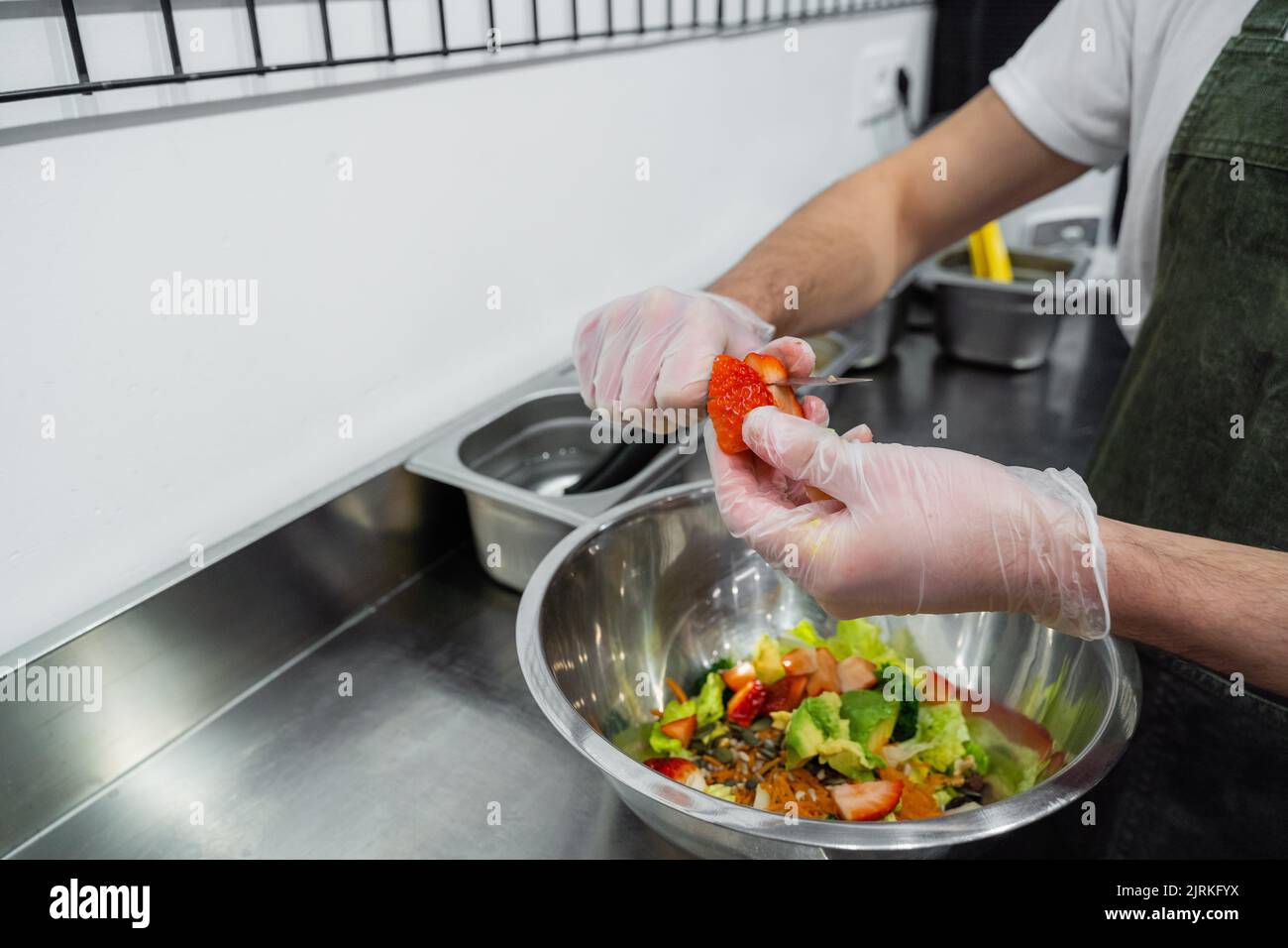 Crop male seller in uniform standing at counter in salad bar and