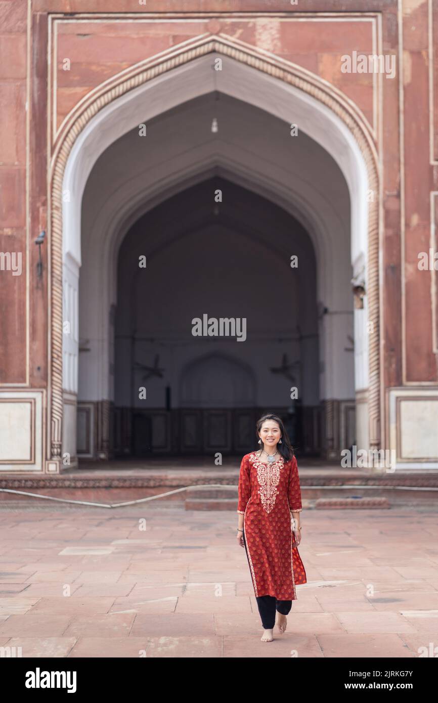 Ethnic young barefoot woman in traditional clothes walking and looking ...