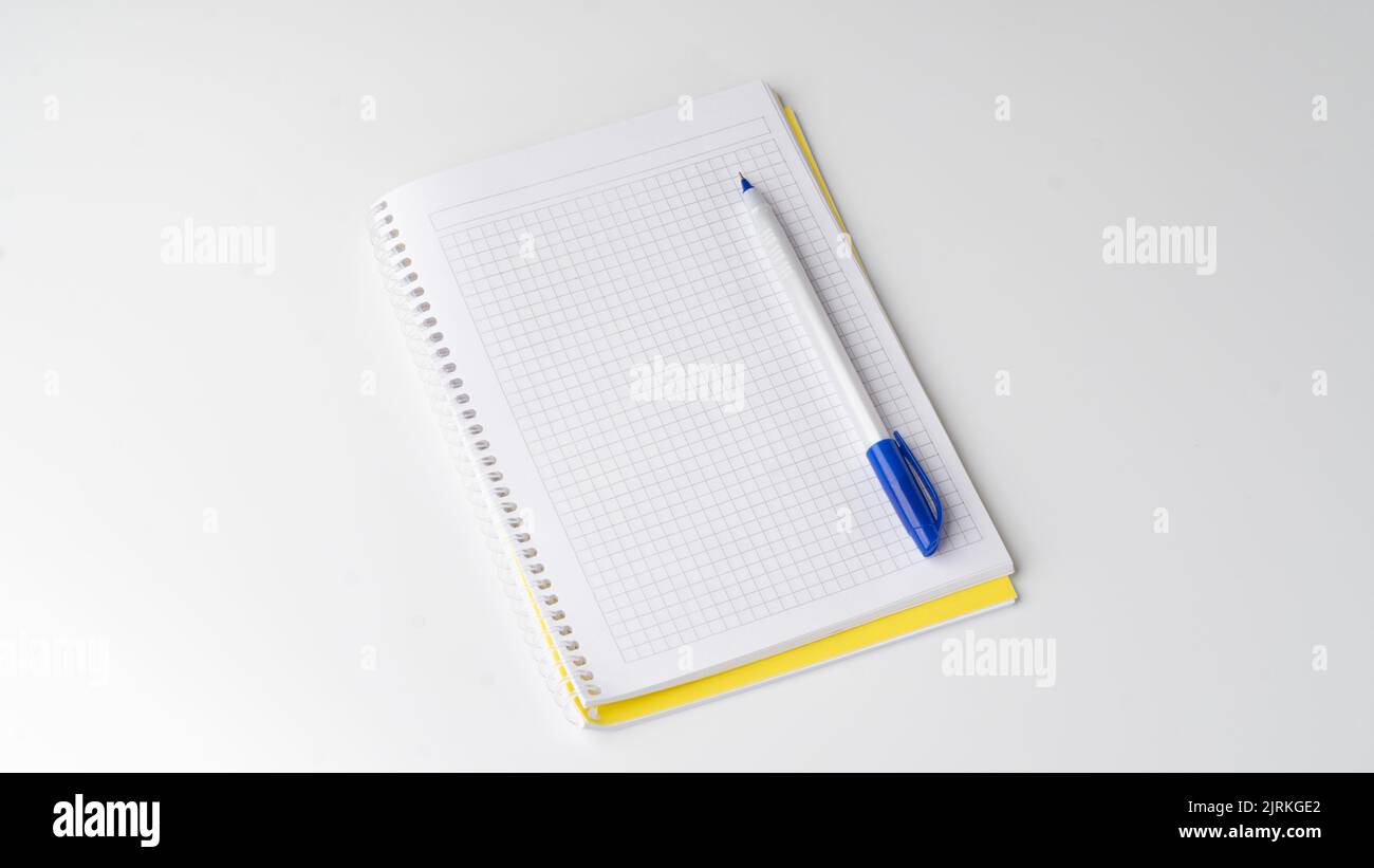 Checkered notebook with pen on white background, space for inscription. High quality photo Stock Photo