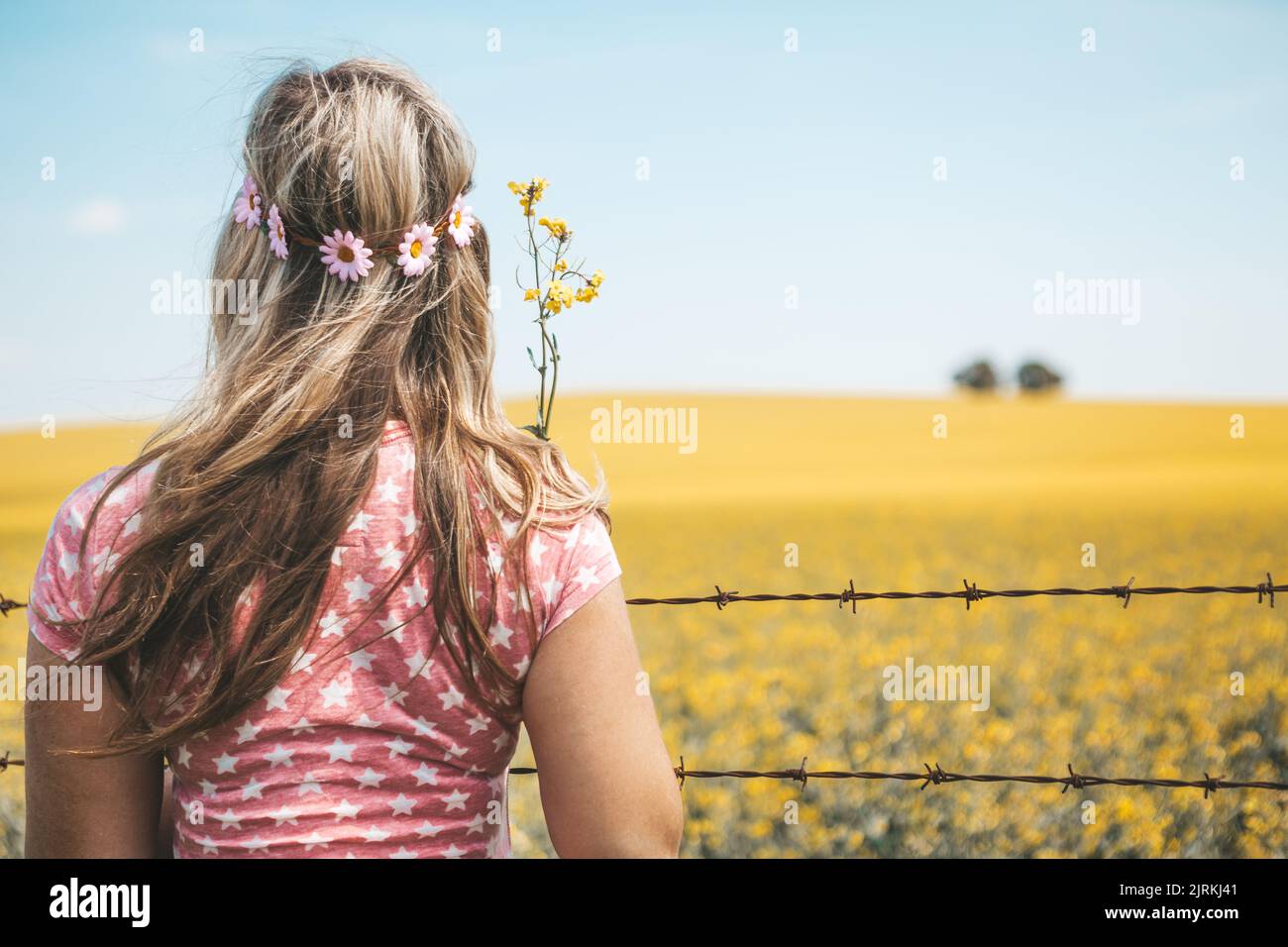 Woman standing by fields of flowering canola in Spring. Stock Photo