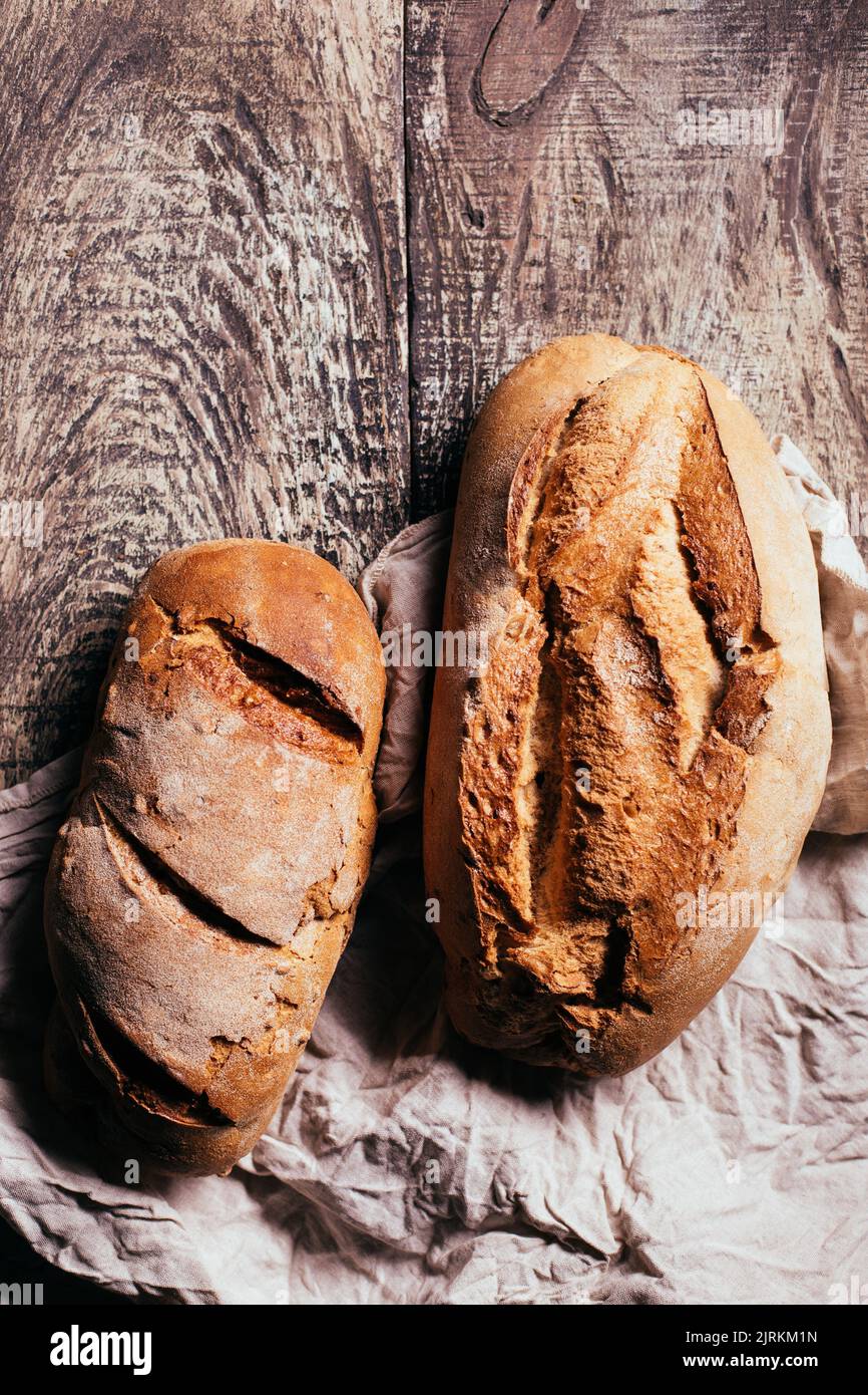 Top view of freshly baked delicious sourdough breads of various shapes placed on wooden table in bakery Stock Photo