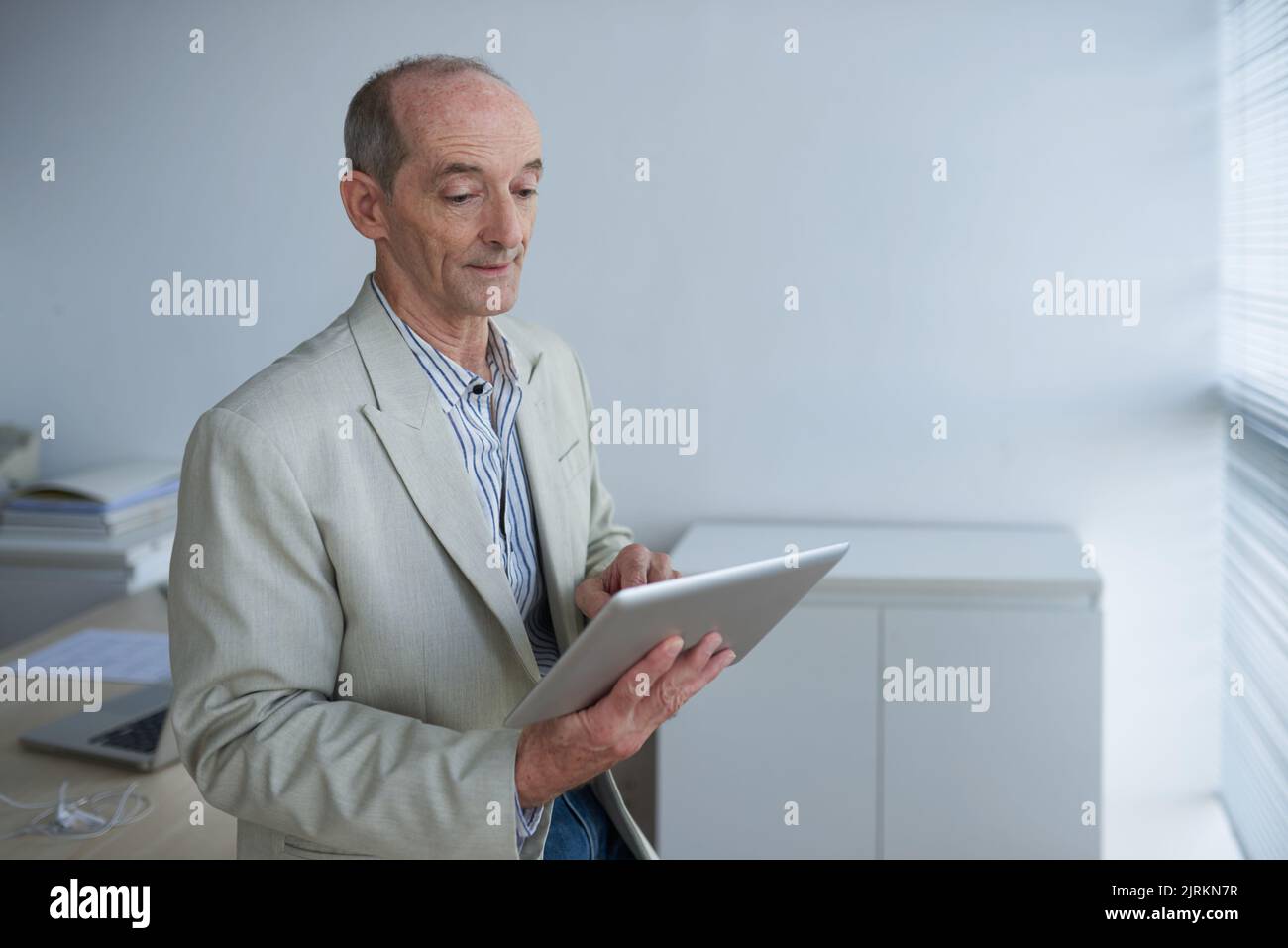 Aged business executive using application on digital tablet Stock Photo