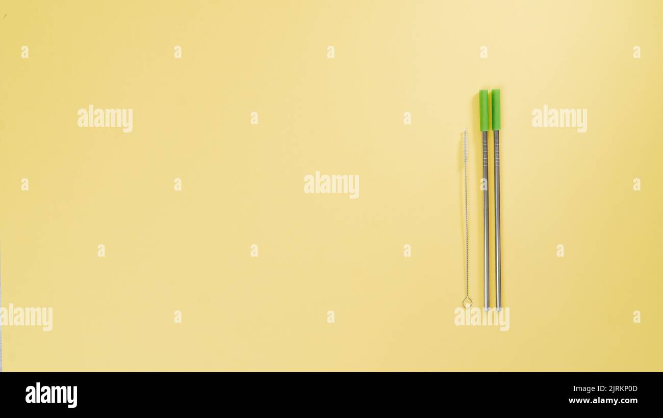 Metal straws for drinks and a brush for cleaning them on a yellow background. High quality photo Stock Photo