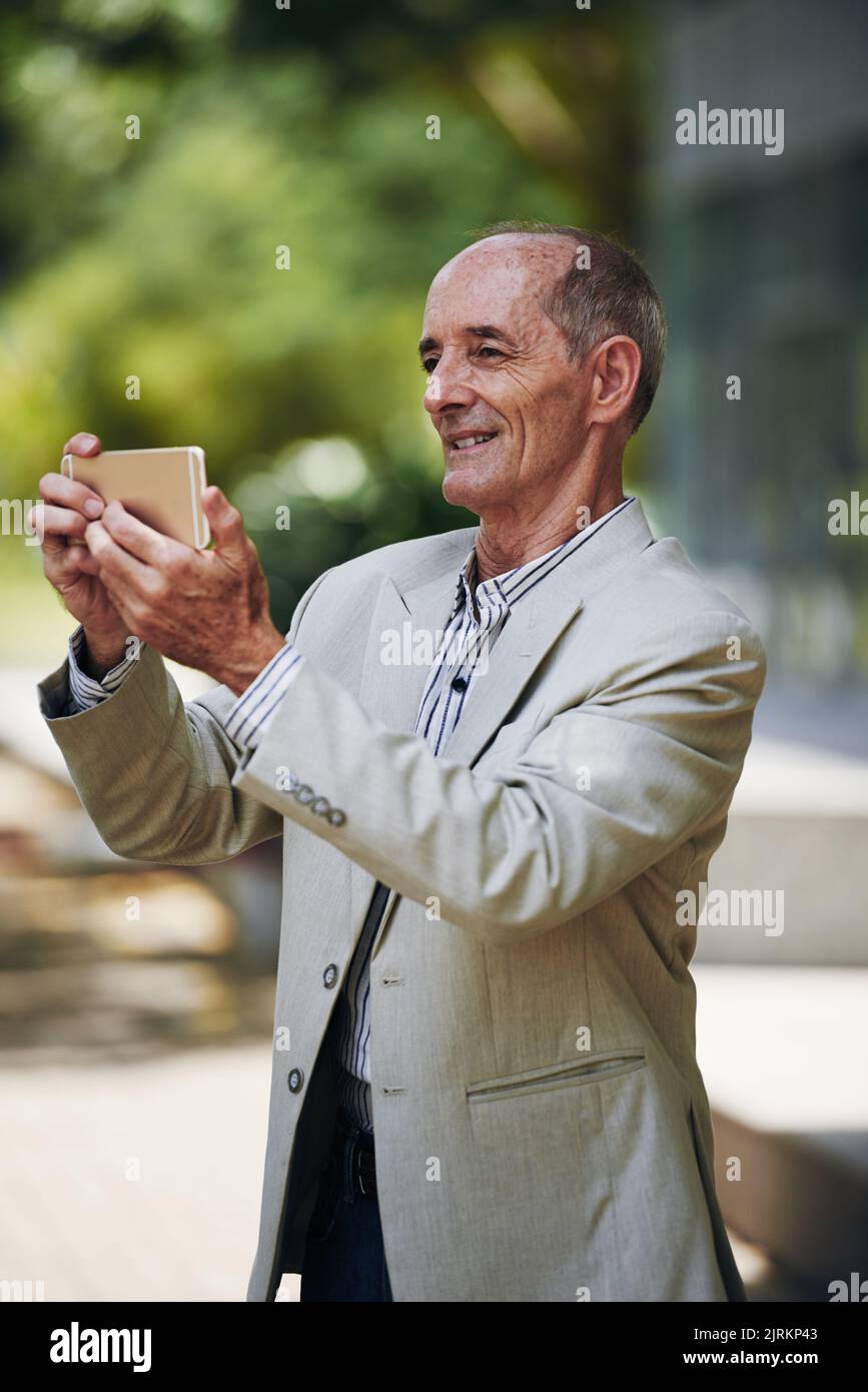 Joyful aged man taking selfies or shooting a video outdoors Stock Photo