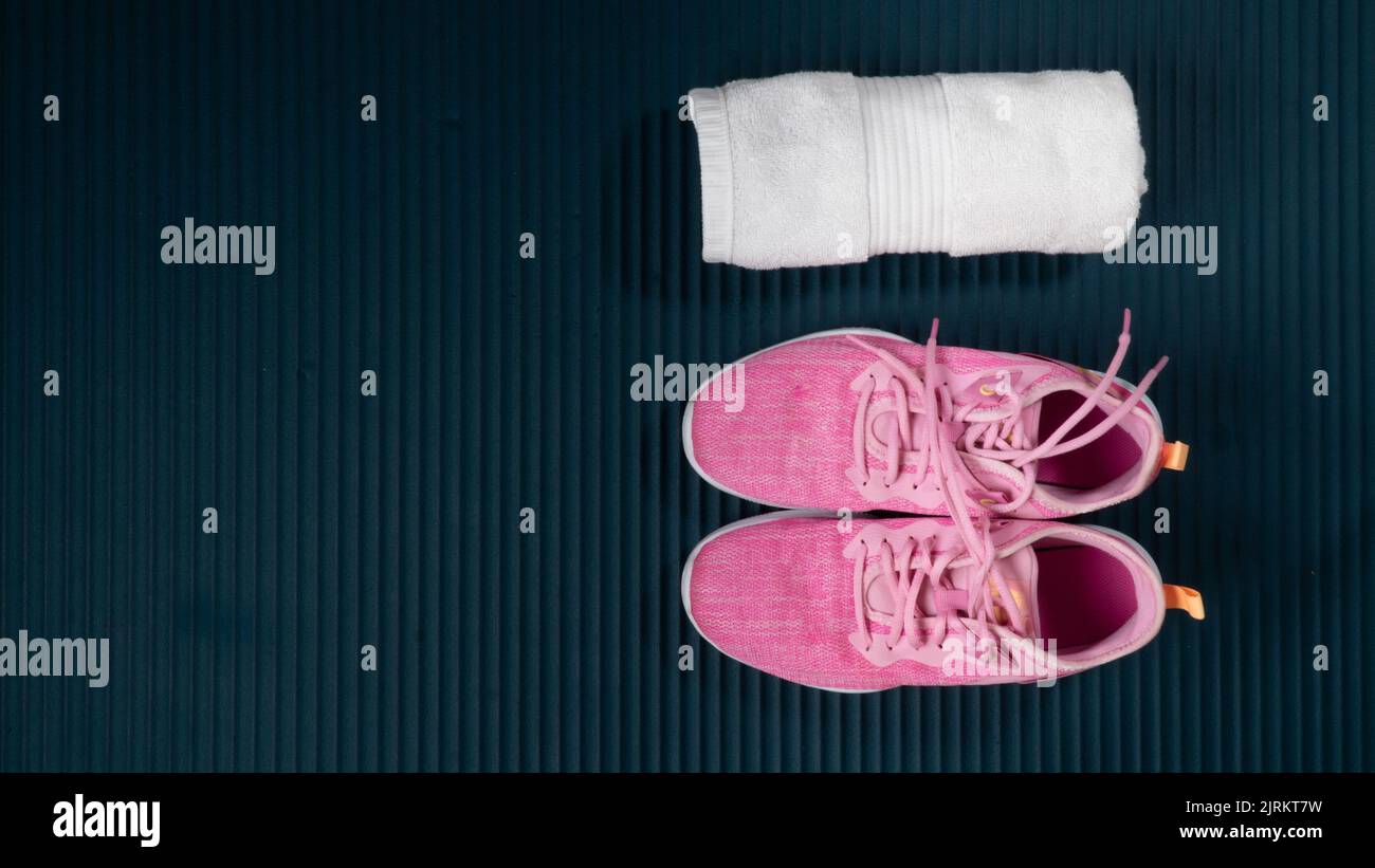 Sneakers and rolled up towel on a workout mat with space for text. High quality photo Stock Photo