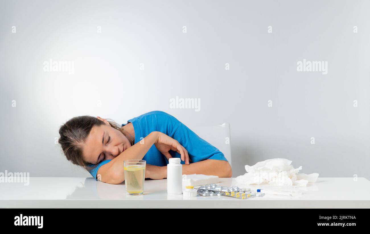 A sick woman without strength lies on the table next to the pills. High quality photo Stock Photo