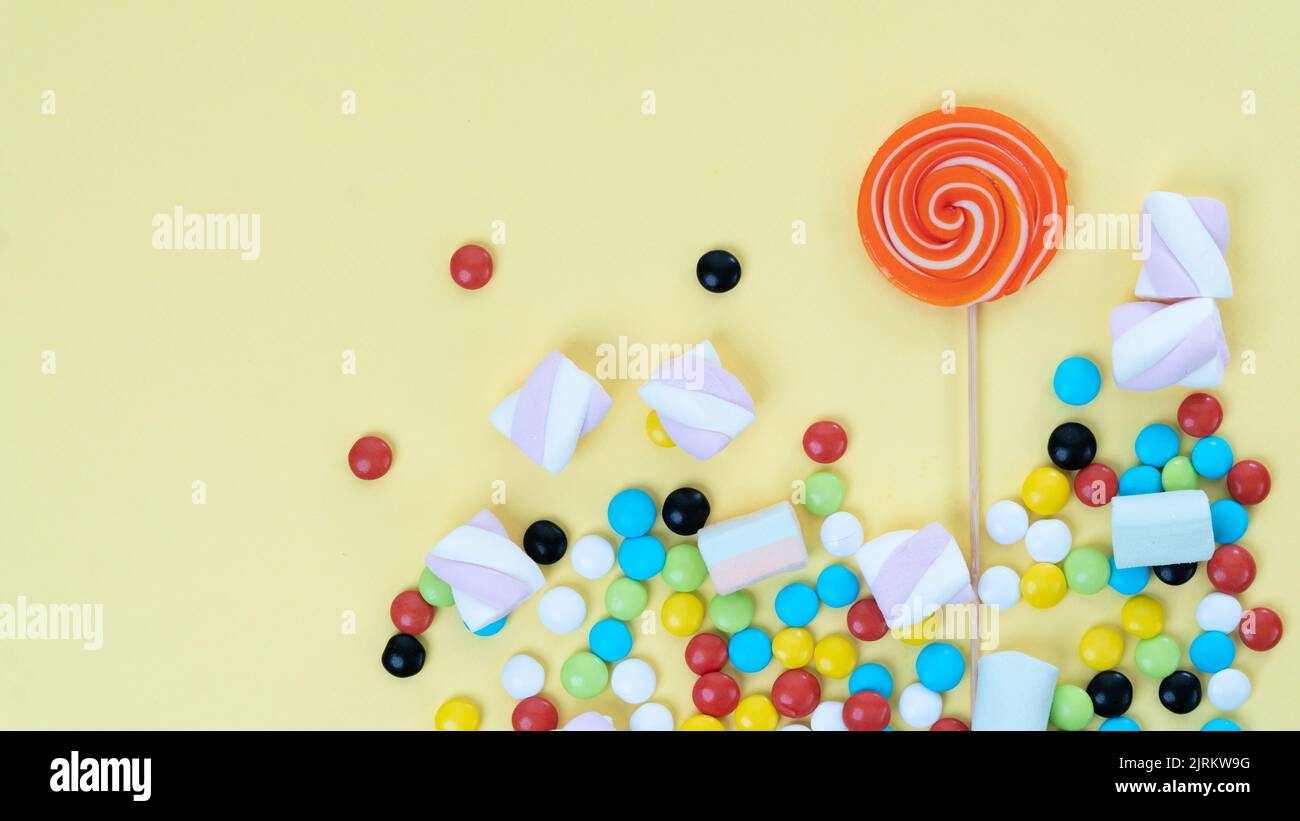 Mix of sweets - lollipop, sweets, marshmallows on a yellow background with a place under the text. High quality photo Stock Photo